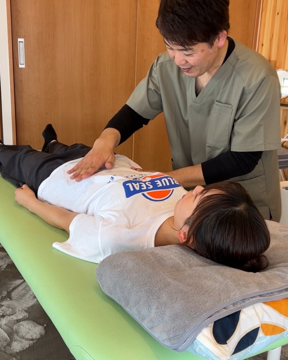 院長が、笑顔で、横になった方のお腹まわりに手を添えて、動きを確認している様子
